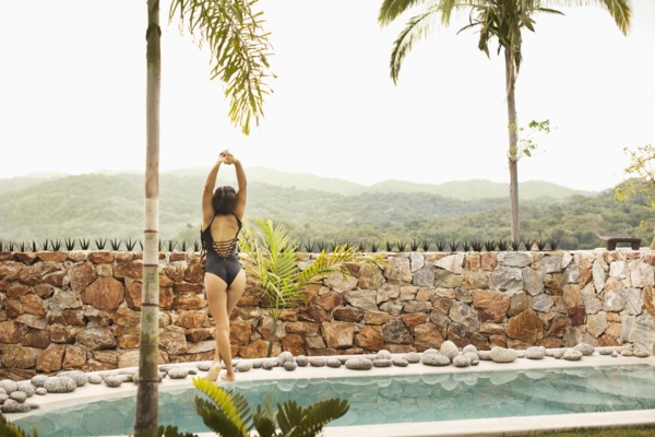 Hispanic woman stretching by swimming pool