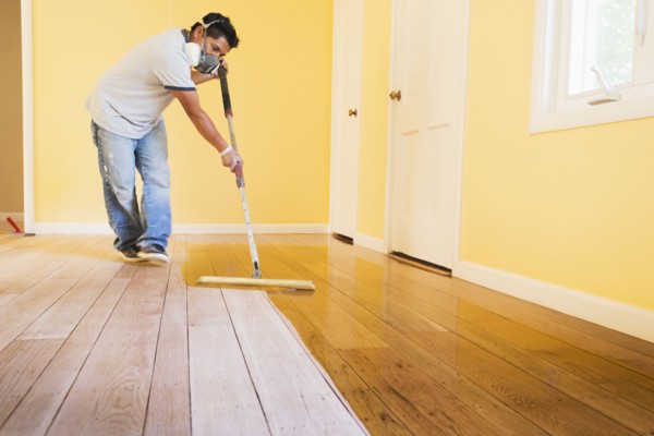 Hispanic man refinishing floors in new house