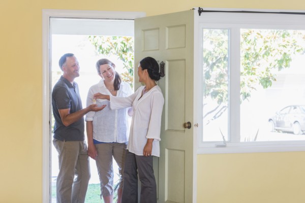 Real estate agent giving couple keys to new home