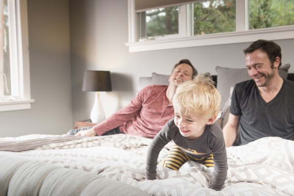 Caucasian fathers playing on bed with son