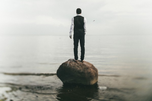 Caucasian man standing on rock at beach