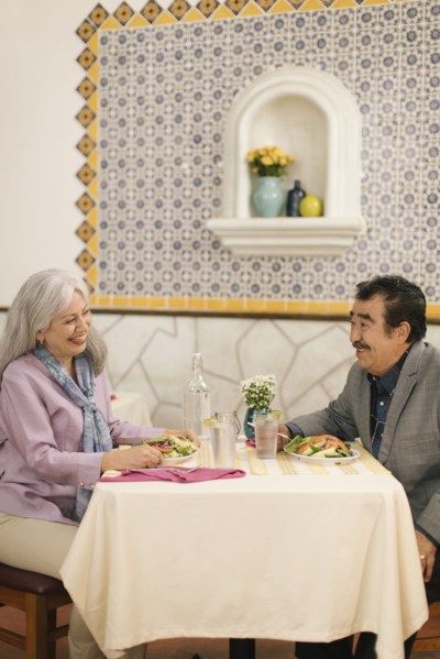 Smiling older couple eating salad and laughing in restaurant