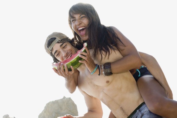 Woman eating watermelon getting piggy back ride from boyfriend