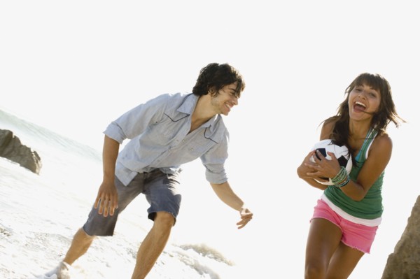 Couple playing with soccer ball on beach