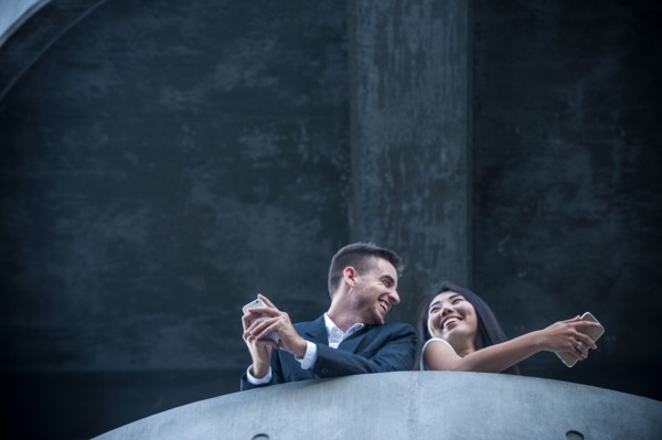 Low angle view of couple on balcony texting on cell phones