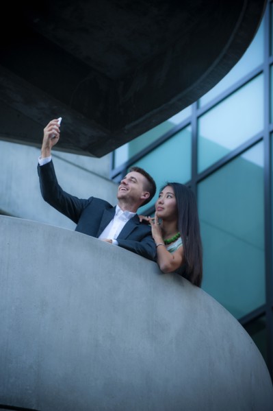 Low angle view of couple on balcony posing for cell phone selfie