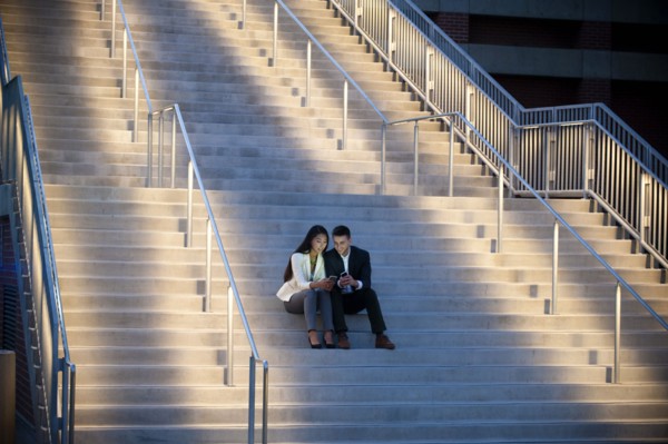 Couple sitting on staircase texting on cell phones