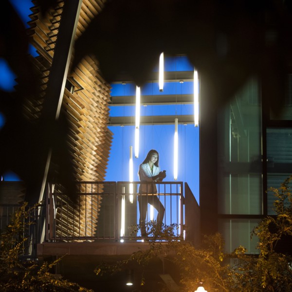 Businesswoman on balcony texting on cell phone at night