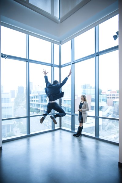 Businesswoman watching businessman celebrating near window