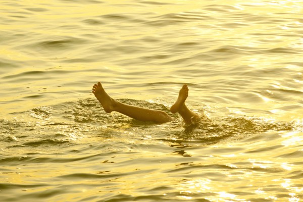 Feet of Caucasian boy sticking out of water