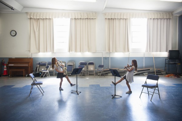 Caucasian girls practicing violins and dancing