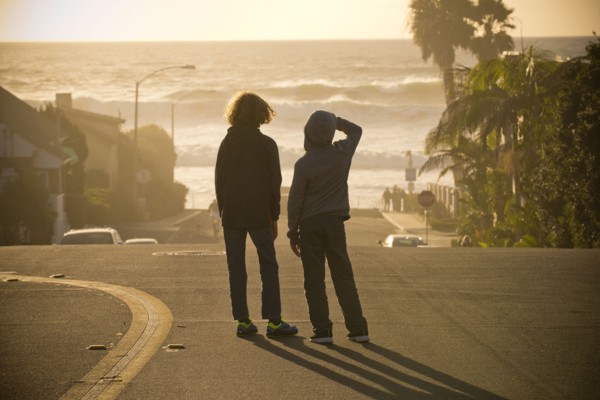 Boys standing in street admiring ocean waves