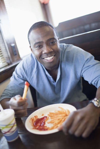 Black man eating french fries at diner