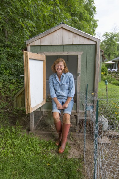 Older Caucasian woman smiling at chicken coop