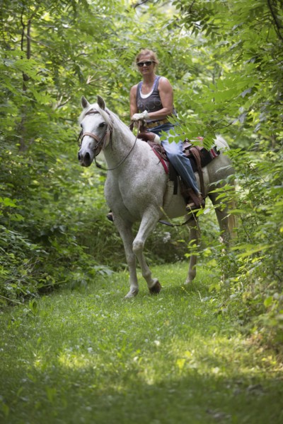 Caucasian woman riding horse in rural field