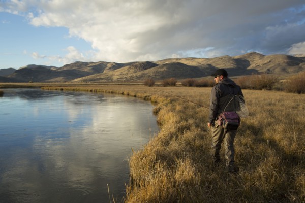 Man carrying fishing supplies near river