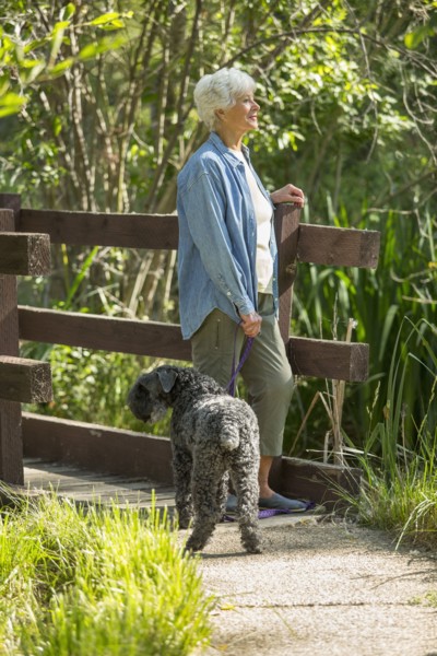 Older Caucasian woman walking dog in park