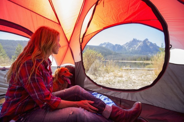 Caucasian woman and dog in camping tent
