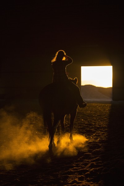 Caucasian woman riding horse in barn