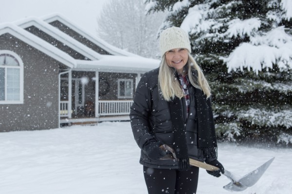 Older Caucasian woman shoveling snow in front yard