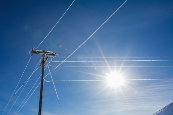 Sun in blue sky and frosty power lines