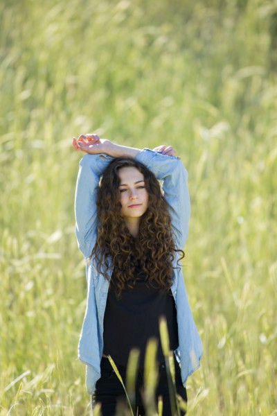Caucasian woman with arms raised standing in field of tall grass