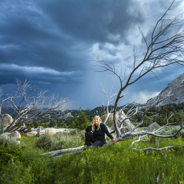 Caucasian woman sitting on fallen tree under clouds