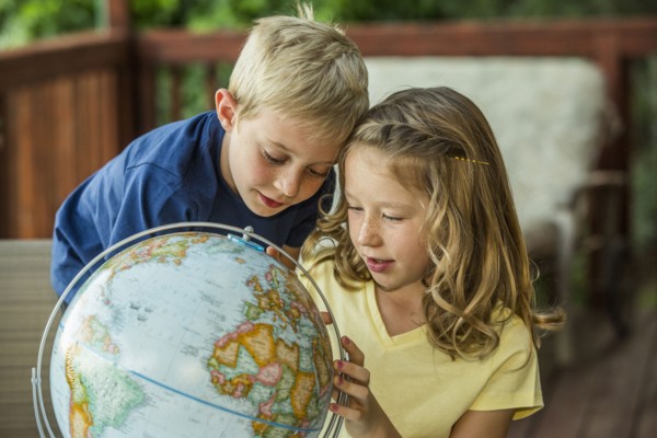 Caucasian brother and sister examining globe
