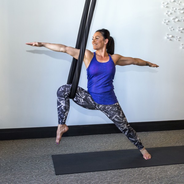 Mixed Race woman performing yoga hanging from silks