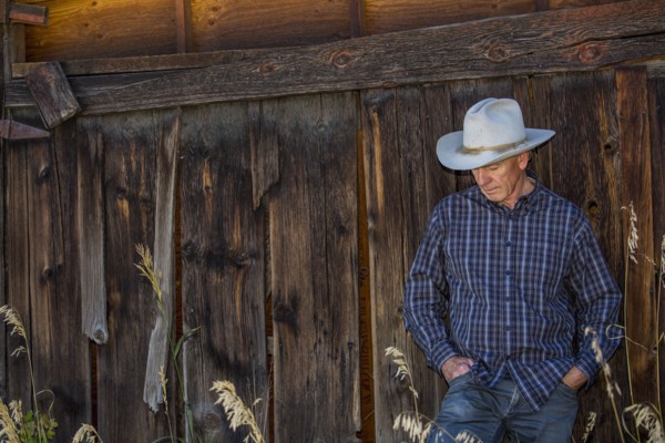 Pensive Caucasian farmer leaning on wooden fence