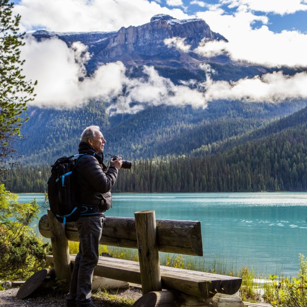 Caucasian man photographing mountain lake