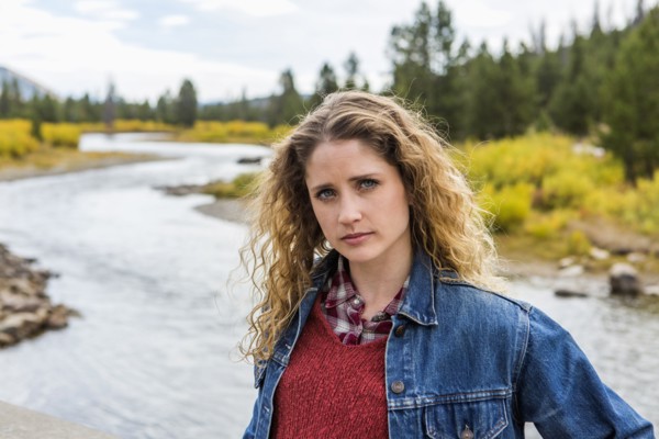 Serious Caucasian woman standing near winding river