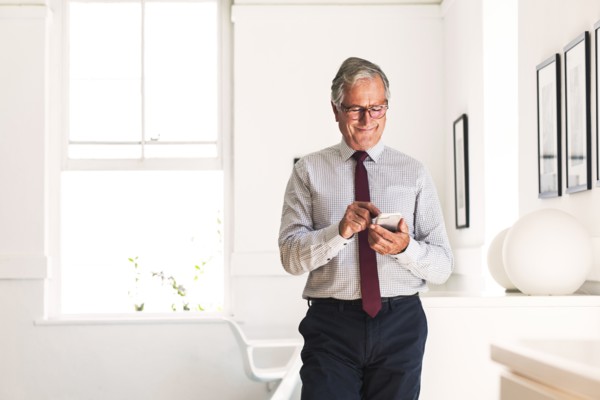 Smiling Caucasian businessman texting on cell phone