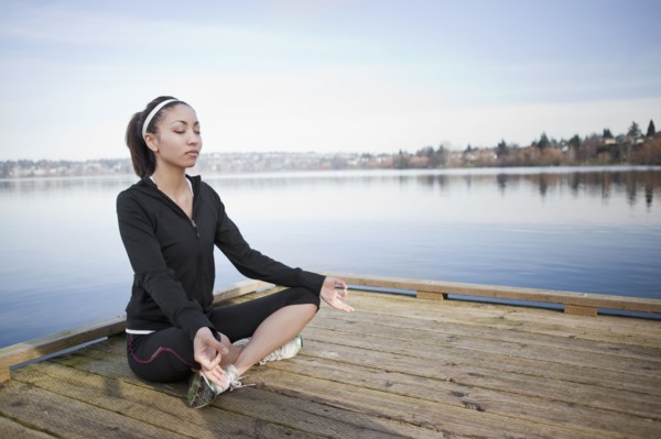 Mixed race woman practicing yoga on pier