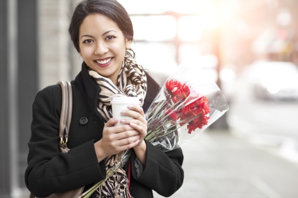 Mixed race woman holding coffee and bouquet of flowers