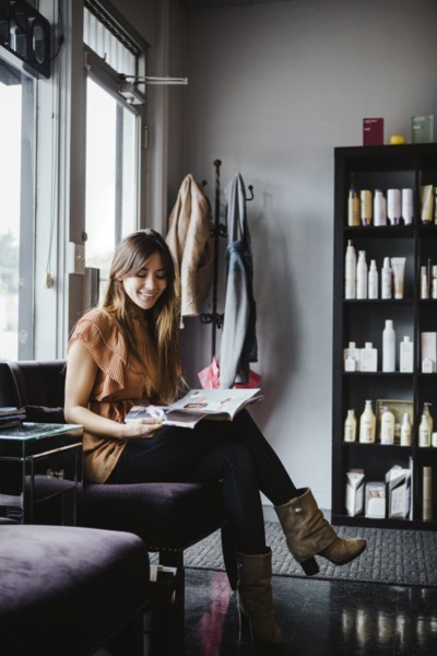 Mixed race woman reading magazine in salon