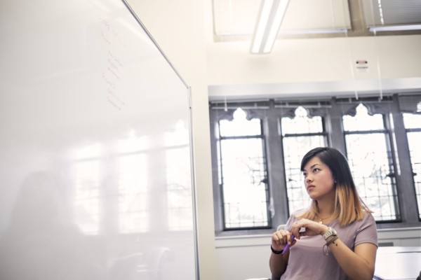 Chinese woman holding marker reading whiteboard