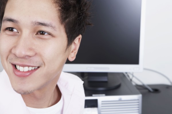 Close up of young Asian man next to computer