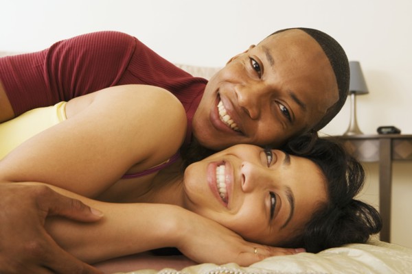 African couple hugging on bed
