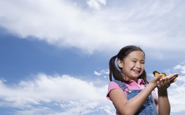 Young Asian girl holding butterfly outdoors