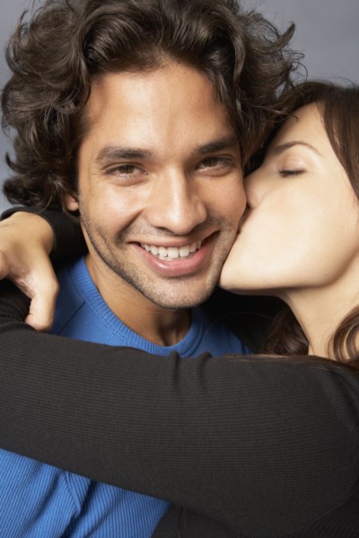 Hispanic woman hugging and kissing boyfriend