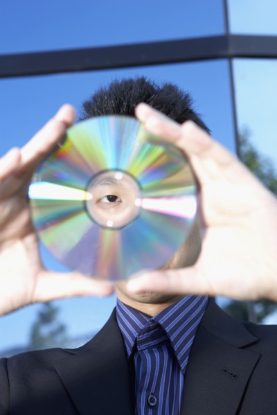 Asian businessman looking through center of cd