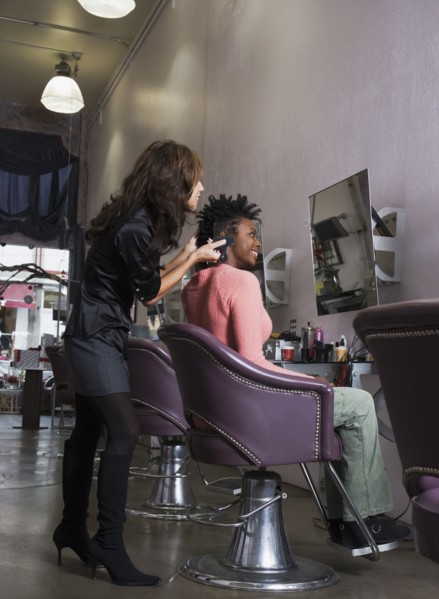 Hispanic hair stylist styling African woman's hair