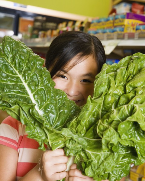 Asian girl holding green leaf vegetables