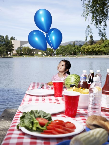 Girl holding balloons at picnic