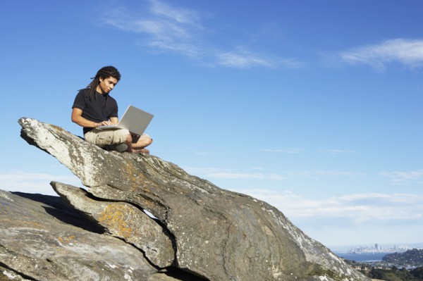 Man using laptop on rock