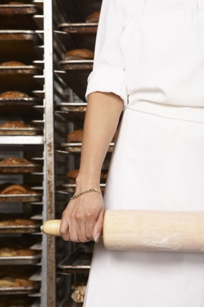 Hispanic baker holding rolling pin in bakery