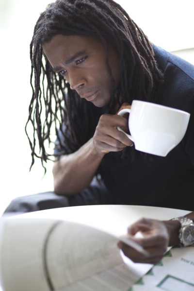 Mixed race businessman drinking coffee and reviewing report