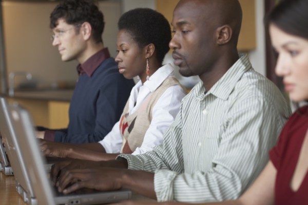 Multi-ethnic people typing on laptops