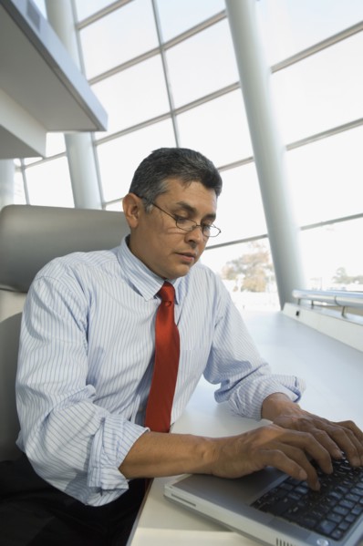 Hispanic businessman typing on laptop